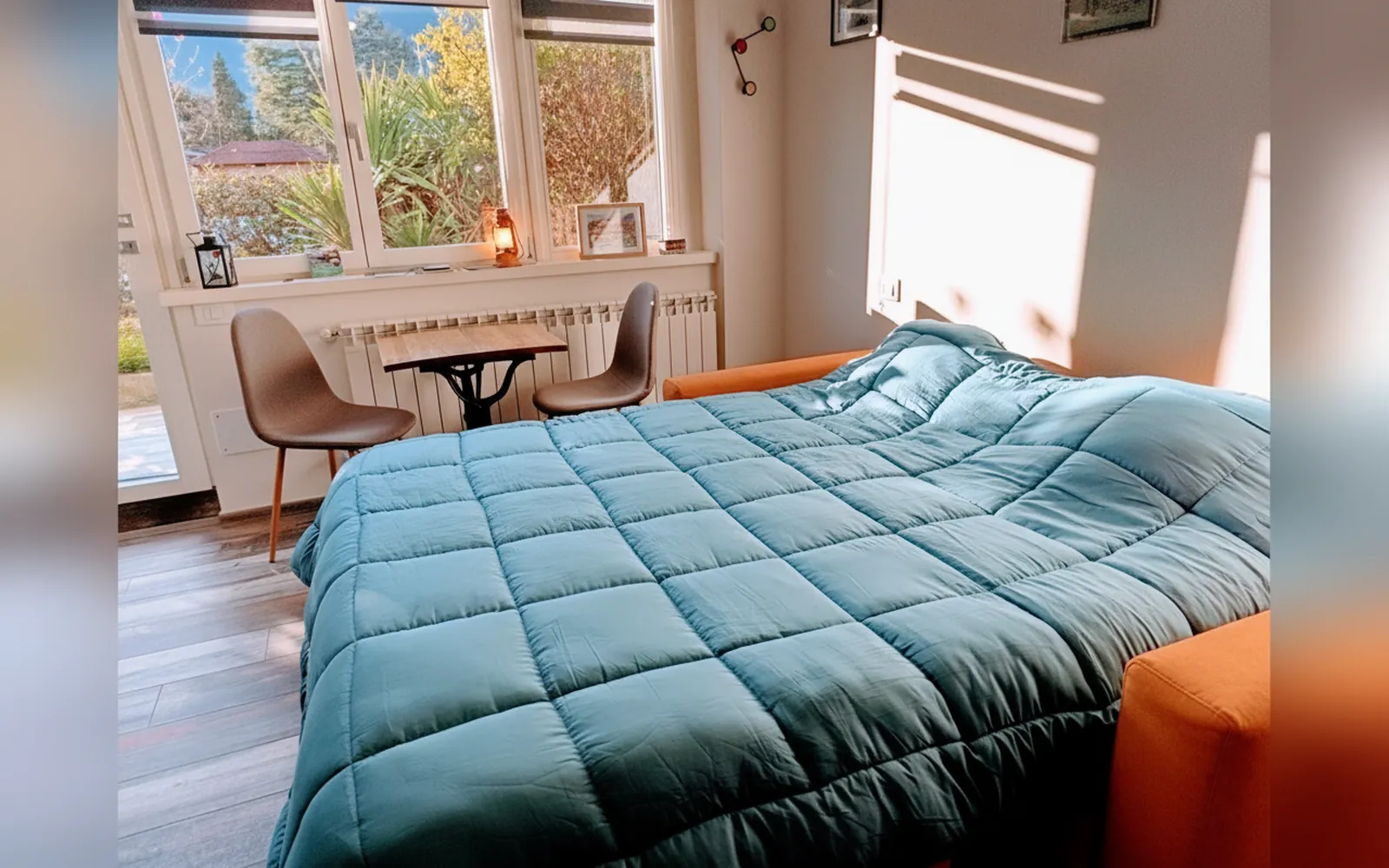 Il letto con il piumone azzurro davanti alle vetrate sul giardino